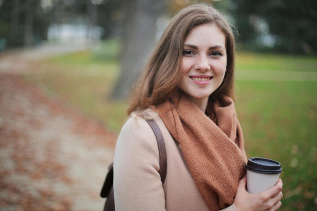 Young brunette woman smiling while holding a coffee