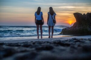 Two Women Standing Near Body of Water