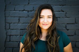 Woman smiling in front of black brick wall